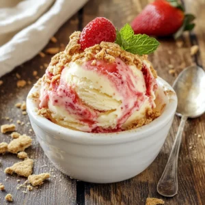 A scoop of Strawberry Cheesecake Ice Cream in a rustic white bowl, garnished with a fresh strawberry slice, crushed graham crackers, and a mint sprig.